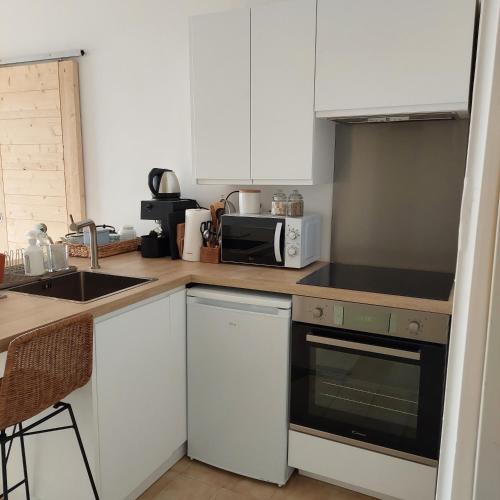 une cuisine avec des armoires blanches et un four à plaques de cuisson dans l'établissement Un balcon sur la mer, à Ajaccio