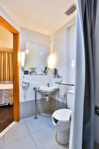 a bathroom with a toilet and a sink and a mirror at San Diego Express Barro Preto in Belo Horizonte