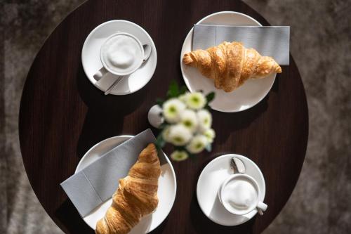 a table with plates of croissants and cups of coffee at Galerie Hotel in Bad Reichenhall