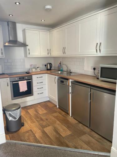 a kitchen with white cabinets and stainless steel appliances at Arkleside Country Guest House in Reeth