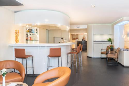 a kitchen with a bar with stools at Galerie Hotel in Bad Reichenhall