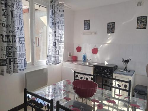 uma pequena cozinha com uma mesa de vidro e um fogão em Appartement le labyrinthe du peintre em Bransat