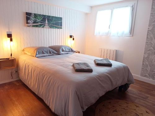 een slaapkamer met een groot bed en 2 handdoeken bij Charmant T2 proche plage avec terrasse privative in Royan