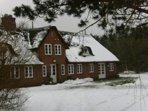 a red house with snow on top of it at Hackerhof-Suedwohnung in Morsum