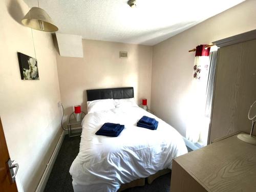 a bedroom with a bed with two blue pillows on it at 2 Bedroom Holiday Apartment Skegness - Flat 18 in Skegness