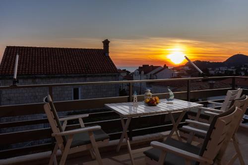 a table and chairs on a balcony with the sunset at Apartments Villa Falkoni in Dubrovnik