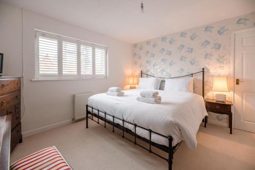 um quarto com uma cama com lençóis brancos e papel de parede azul em Greenbanks Orford Air Manage Suffolk em Woodbridge
