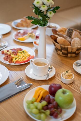 a wooden table topped with plates of food and fruit at Galerie Hotel in Bad Reichenhall