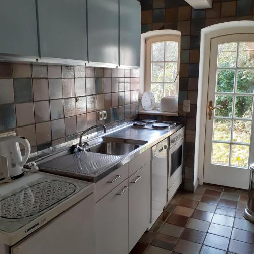 a white kitchen with a sink and a stove at Hackerhof-Suedwohnung in Morsum