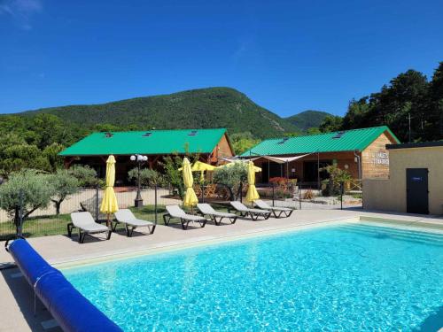 a pool with chairs and umbrellas next to a house at Les Chalets de Saint Maurice (Dieulefit) in Dieulefit