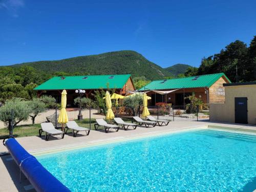 - une piscine avec des chaises et des parasols à côté d'une maison dans l'établissement Les Chalets de Saint Maurice (Dieulefit), à Dieulefit