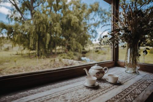 a table with two cups and a vase on a window at Ginger and Coco in Tandil