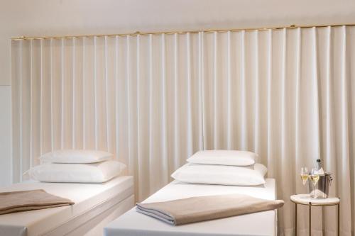two beds in a room with white curtains at Galerie Hotel in Bad Reichenhall