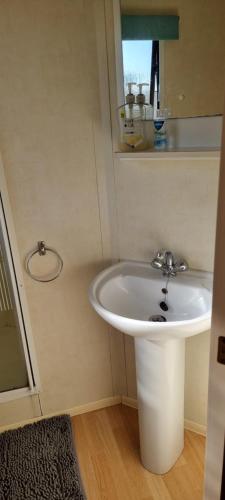 a bathroom with a white sink and a mirror at Lovely Caravan at Ingoldmells just behind sealands in Ingoldmells