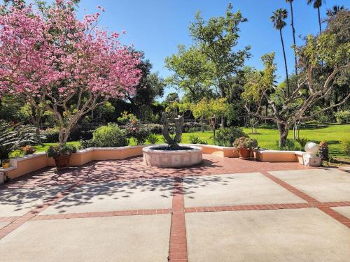 a fountain in a park with trees and pink flowers at 628 Madre Street in Pasadena