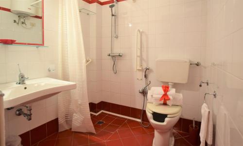 a bathroom with a toilet and a sink with a red bow on it at Hotel Iride by Marino Tourist in San Vito lo Capo