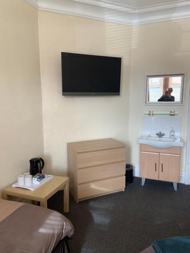 a room with a television and a bed in it at Melrose Guest House in Whitley Bay