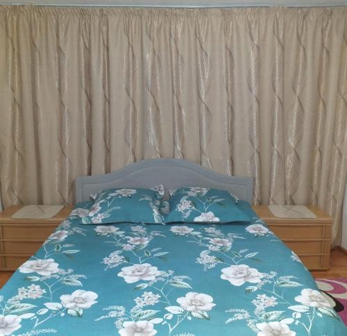 a bed with a blue comforter with white flowers at Cabana La Cucu in Vadu Moţilor