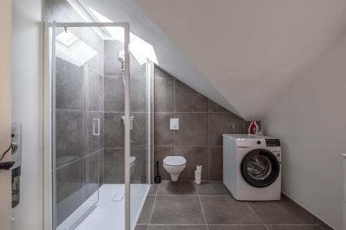 a bathroom with a shower and a washing machine at Liberation in Pontault-Combault