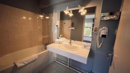 y baño con lavabo, bañera y espejo. en Hotel des Voyageurs, en Tarnac