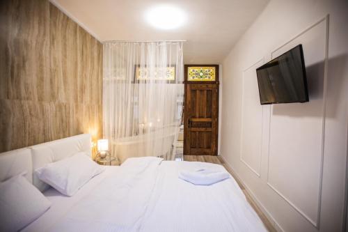 een slaapkamer met een wit bed en een televisie bij Стильна квартира в центрі на Площі Ринок вулиця Галицька 9 in Lviv
