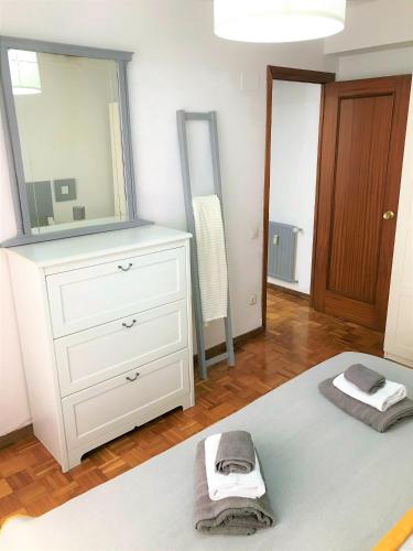 1 dormitorio con tocador blanco y espejo en Tranquilidad al lado del Centro Parking incluido, en Oviedo