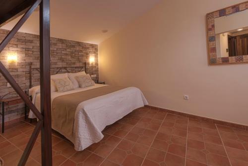 a bedroom with a bed and a brick wall at Hostal EL GRIEL NO DISPONEMOS DE RECEPCIÓN FÍSICA in Hervás