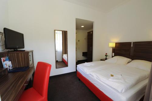 a bedroom with a bed and a desk and a red chair at Best Western Hotel Kaiserhof in Bonn