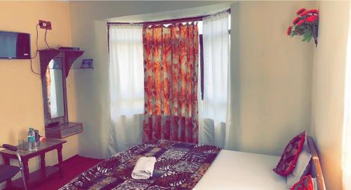 a bedroom with a bed and a window with a curtain at Hotel Young Mamta in Srinagar
