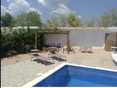 eine Terrasse mit einem Pool, einem Tisch und Bänken in der Unterkunft Lo raconet 2 in L'Ampolla