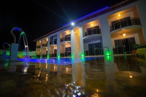 a building with a swimming pool at night at Pousada Kalunga in Flecheiras