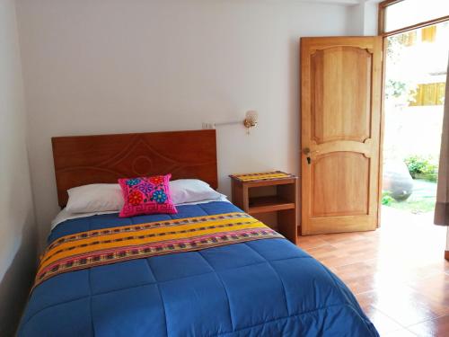 um quarto com uma cama com uma cabeceira de madeira e uma porta em Kentis Home Ollantaytambo em Ollantaytambo