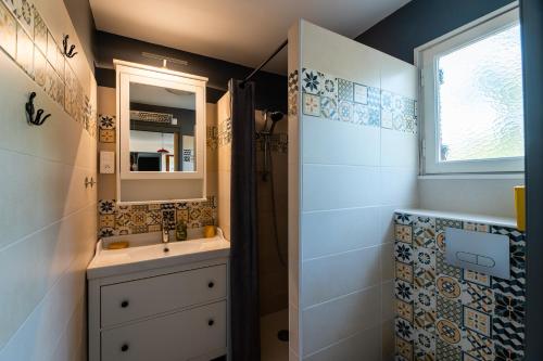 La salle de bains est pourvue d'un lavabo, d'un miroir et d'une douche. dans l'établissement LA PETITE MAISON DU LAC, à Biscarrosse