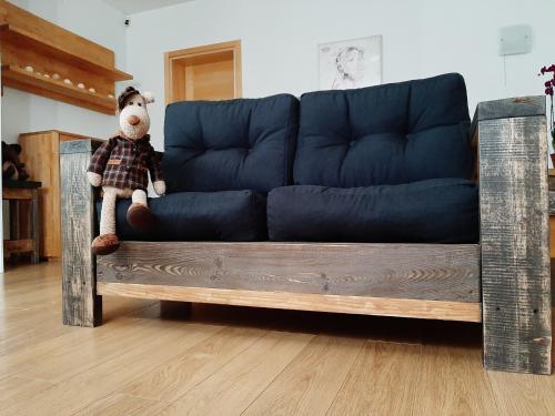a teddy bear sitting on a blue couch at Champêtre Park View Apartments in Rīga