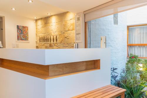 a lobby with a white counter and a bench at La Morada Petit Hotel in Neuquén