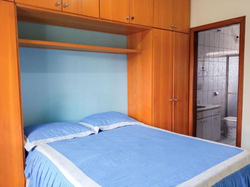 a bedroom with a blue bed and a bathroom at Casa Azul Antares 3 Quartos - Pet Friendly in Londrina