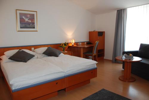 a bedroom with a bed and a desk and a chair at Sporthotel Podersdorf in Podersdorf am See
