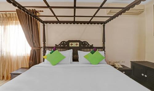 a bedroom with a large bed with green pillows at Treebo Anchor Inn in Cochin
