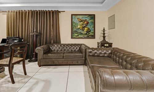 a living room with a leather couch and a table at Treebo Anchor Inn in Cochin