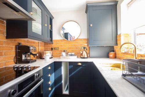 una cocina con armarios azules y fregadero en Beautiful Luxe Victorian Townhouse - 5 mins walk from Warwick Castle & town, en Warwick
