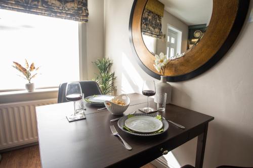 a table with two glasses of wine and a mirror at Luxury Townhouse - close to castle & town - perfect stylish stay, sunny private courtyard, dog friendly in Warwick