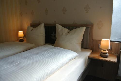 a bedroom with a bed with white sheets and two lamps at Haus Drei Könige in Balve