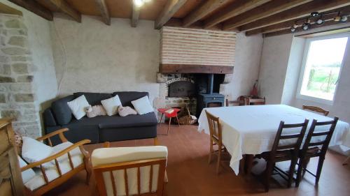 ein Wohnzimmer mit einem Tisch, einem Sofa und einem Kamin in der Unterkunft Le Champ des Fougères in Vicq-Exemplet