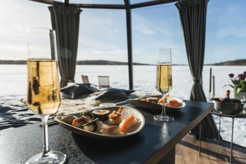 einen Tisch mit einem Teller Essen und zwei Gläsern Champagner in der Unterkunft Northern Lights Glass Igloo Getaway For Couples in Rovaniemi