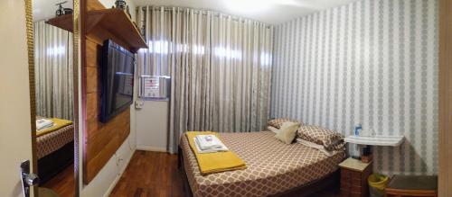 um pequeno quarto com uma cama com um cobertor amarelo em ACONCHEGANTE QUARTO - PRAIA do CANTO em Vitória