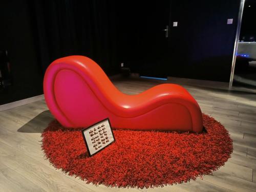 une chaise rouge assise au-dessus d'un tapis rouge dans l'établissement Le BLACK DIAMOND, à Incheville
