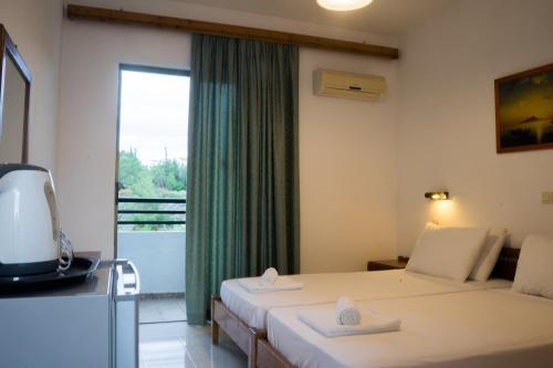 a hotel room with two beds and a window at Lilly Apartment in Faliraki