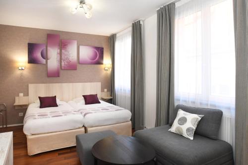a hotel room with two beds and a chair at Logis Hôtel du Centre - Halte idéale en cyclotourisme avec garage à vélos clos in Molsheim
