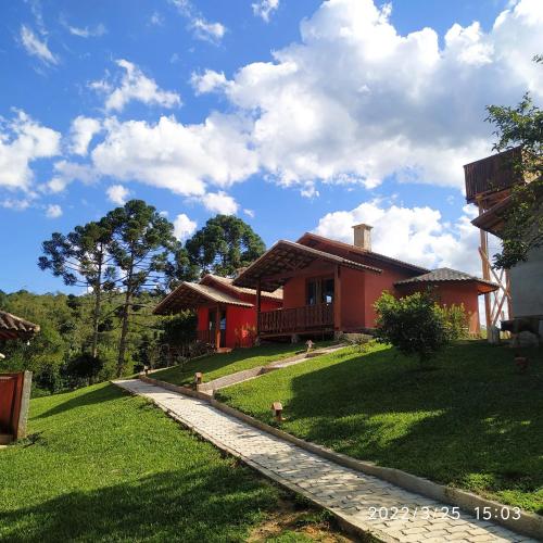 a red house on a green lawn with a pathway at Pousada Vale da Cachoeira in Visconde De Maua