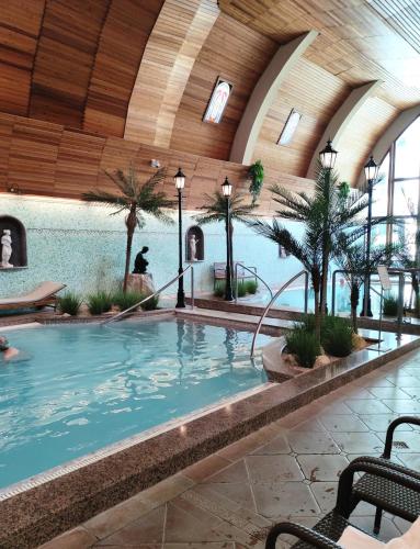 una grande piscina coperta con palme in un edificio di Spa Residence Carbona Apartment 205 a Hévíz